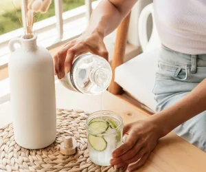 woman pouring water into a glass with lemon