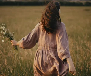 A woman in a brown dress runs across a meadow